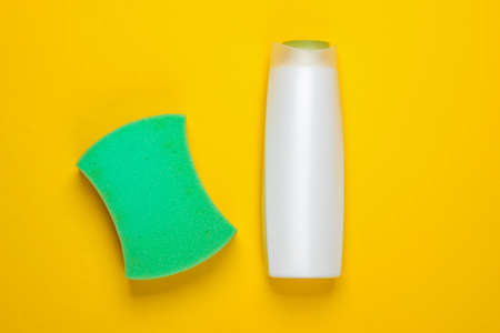 Bath sponge with a bottle of shampoo on a yellow background. Top viewの写真素材