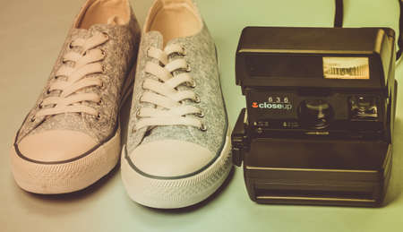 ODESSA, UKRAINE - APRIL 1, 2020: Old fashioned sneakers with retro instant camera on a blue...