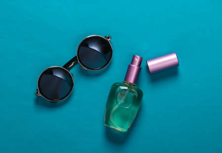 Fashionable round sunglasses and perfume bottle on a blue background. Top viewの写真素材