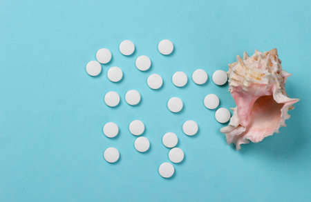 Mineral tablets (calcium) with seashells on a blue backgroundの写真素材