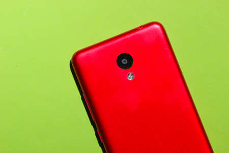 Red smartphone on green background. Top view