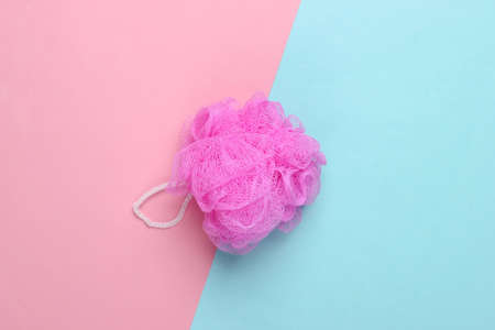 Pink bath sponge on a blue-pink pastel background. Top view. Minimalismの写真素材