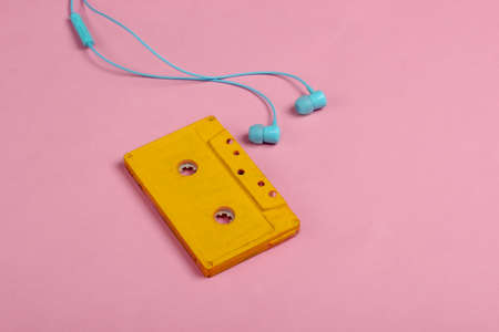 Retro audio cassette with earphones on pink pastel background. 80s. Minimalism.の写真素材