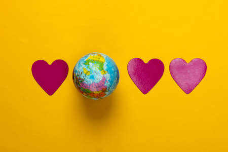 Love for the planet earth. Earth Day. Globe with hearts on a yellow background. Top view