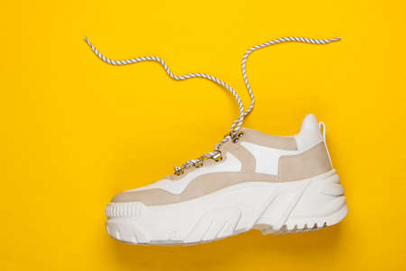 Fashionable sneaker with high soles (platform) on yellow background. Top view. Minimalism