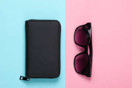 Wallet with sunglasses on a blue-pink pastel background. Women's accessories. Top viewの写真素材