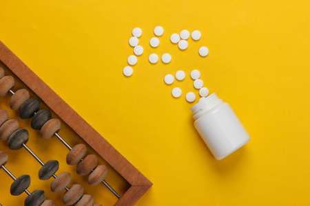 Vintage abacus and pill bottle on yellow background. Top view.