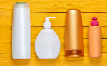 Bottles of shampoos on a yellow wooden background. cosmetics. top viewの写真素材