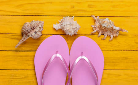 Flip flops with seashells on a yellow wooden background. The concept of a beach holiday, resort. top...