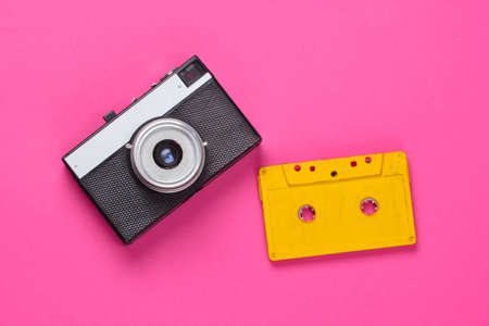 Retro audio cassette and film camera on pink background. 80s. top view. minimalismの写真素材