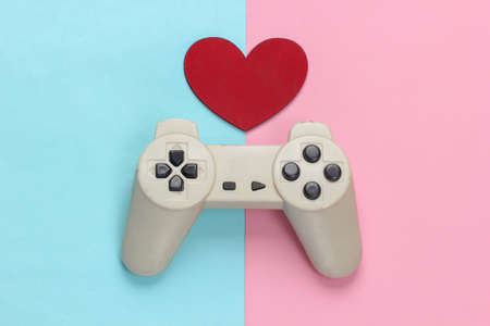 game lover. Retro gamepad with red heart on pink blue pastel background. Retro 80s. top view.