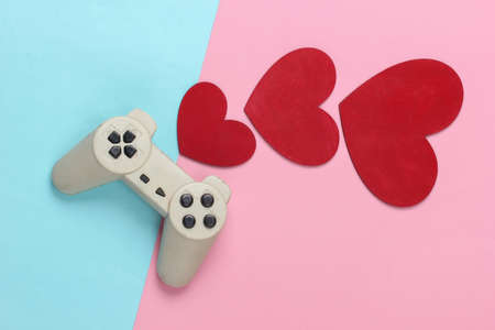 game lover. Retro gamepad with red hearts on pink blue pastel background. Retro 80s. top view.