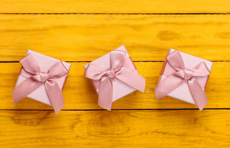 Gift boxes with bows on a yellow wooden background. top viewの写真素材
