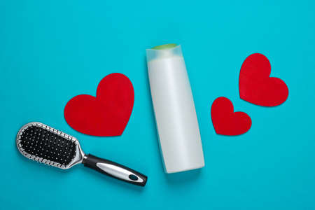 Shampoo bottle, hairbrush with hearts on blue background. beauty and hair care. top view. flat lay. minimalismの写真素材