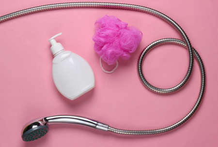 showering. Shower head hose with bath sponge, bottle of shower gel on pink pastel background. top viewの写真素材