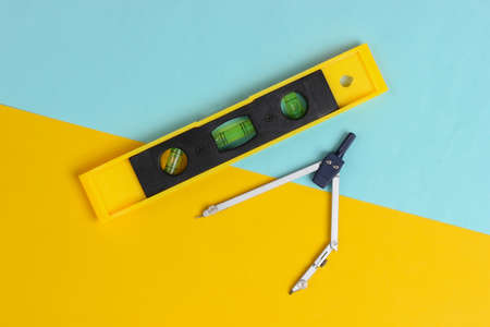 Building level and compass on yellow blue studio background. top view. minimalism