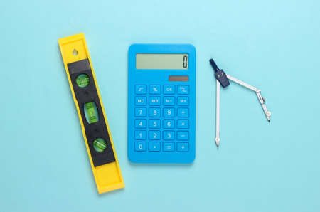 Building level and calculator, compass on blue studio background. building tool. top view. minimalismの写真素材