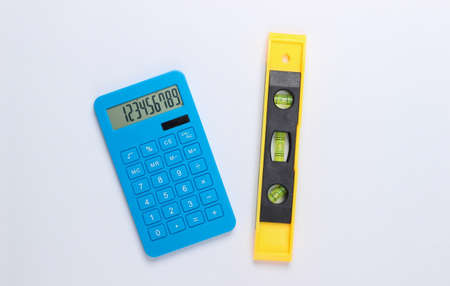 Building level and calculator on white studio background. top view. minimalism