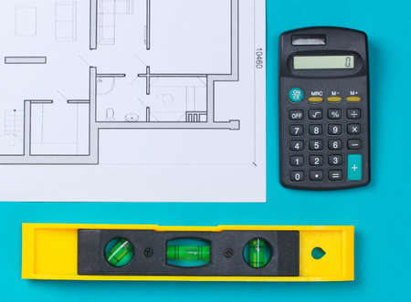 Construction level with building plan (blueprint), calculator on a blue background. top view