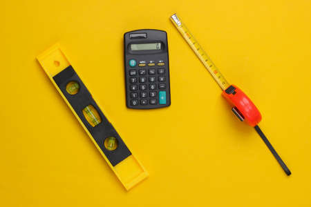 Engineering construction supplies on yellow background. Construction level, ruler, calculator. top viewの写真素材