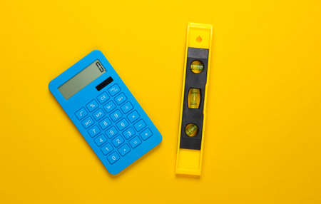 Building level and calculator on yellow studio background. top view. minimalism