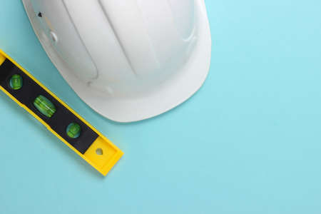 Hard hat with building level on blue studio background. Engineering, construction equipment. top viewの写真素材