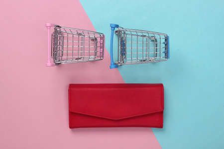 Two mini supermarket trolleys with wallet on blue pink pastel background. shopping concept. top view. minimalismの写真素材