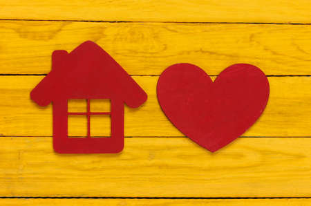 Figurine of house with heart on yellow wooden background. top viewの写真素材