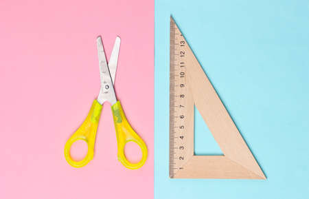 Stationery (school) scissors, triangle ruler on pink blue pastel background. school supplies. top...
