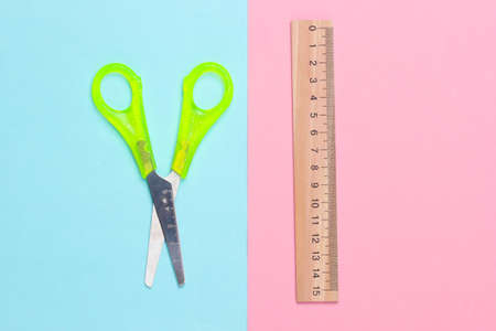 Stationery (school) scissors, ruler on pink blue pastel background. school supplies. top view. minimalismの写真素材