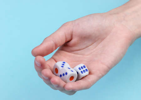 Dice in hand close-up on a blue backgroundの写真素材