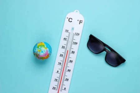 Summer vacation concept. Weather thermometer with sunglasses, globe on a blue background. climate...