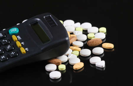 Pills and calculator on a black background.