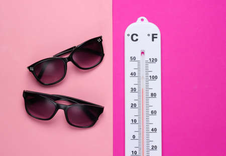 Summer vacation concept. Weather thermometer with sunglasses on pink background. Top viewの写真素材