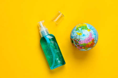 Antiseptic bottle and globe on yellow background. Disinfectant.Top view
