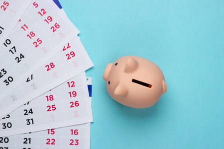 Piggy bank with a monthly calendar on a blue background. Payment of rental housing or loans. Top viewの写真素材