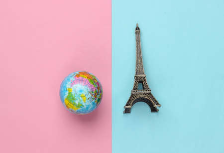 Minimalism travel still life. Figurine of the Eiffel tower, globe on pink blue pastel background.の写真素材