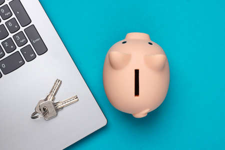 Laptop with keys, piggy bank on a blue background. Top viewの写真素材