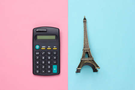 Minimalism travel still life. Figurine of the Eiffel Tower, calculator on pink blue pastel background. Calculation of travel expenses. Top viewの写真素材