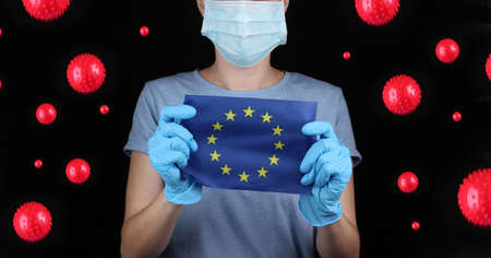 Woman in face mask and gloves holding EU flag on black background with virus strain.の写真素材