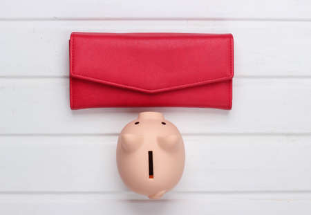 Piggy bank with red leather wallet on white wooden background. Top viewの写真素材