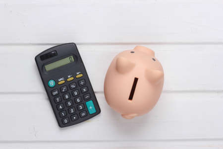 Piggy bank and calculator on white wooden background. Top viewの写真素材