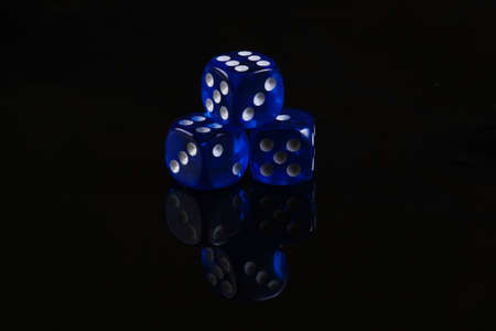 Blue dice on a black background. Game addiction. Luck