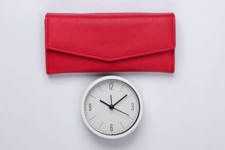 Time to make money. Deposit. White clock and red wallet on white background. Minimalistic studio...