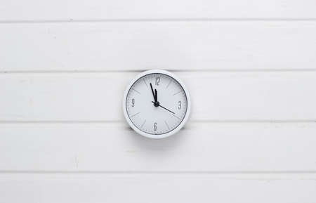 White clock on white wooden background. Time running away. Top viewの写真素材