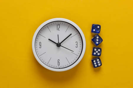Good luck time. White clock with dice on yellow background. Top view. Flat layの写真素材