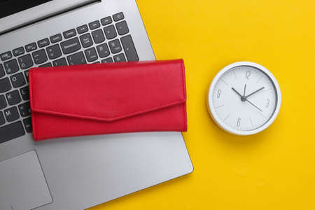 Time to make money.Online business. White clock, laptop and red wallet on yellow background....