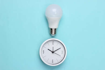 Clock with light bulb on blue background. I have an idea! Minimalism. Top viewの写真素材