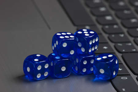 Stack of blue dice on laptop keyboard close up