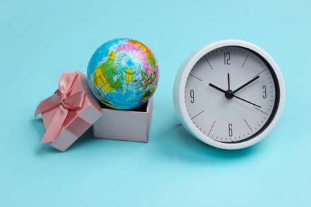 Globe in a gift box and clock on a blue background.の写真素材